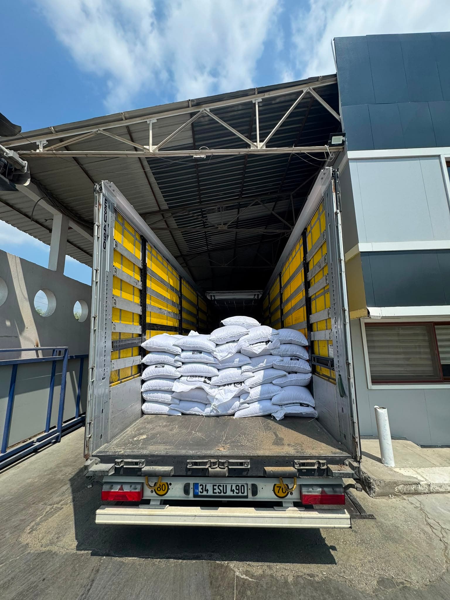 Depo önünde kapıları açık kamyon ve yükler